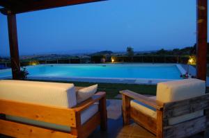 a swimming pool at night with two lounge chairs at Agriturismo Prati degli Orti in Montiano