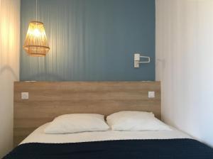 een bed met twee kussens en een licht erboven bij Studio 100m de la mer in Nice