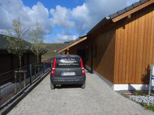 um carro estacionado num passeio ao lado de um edifício em Eifel & See - Ferienhäuser am Waldsee Rieden/Eifel em Rieden