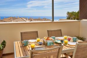 einen Tisch mit Speisen und Orangensaft auf dem Balkon in der Unterkunft Sea View Penthouse, Pool, Privacy, Benalmadena in Benalmádena