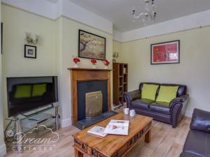 een woonkamer met een bank en een open haard bij Covecastle Cottage in Weymouth