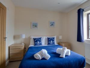 una camera da letto con un letto blu e asciugamani di New Boathouse a Weymouth