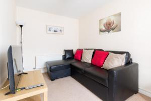 a black leather couch in a living room with a television at 6 Bedroom New Build House in Wolverhampton
