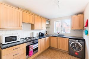 een keuken met houten kasten en een wasmachine en droger bij 6 Bedroom New Build House in Wolverhampton