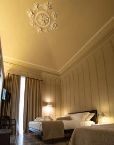 a hotel room with two beds and a chandelier at B&B Palazzo Perrotta in Catania