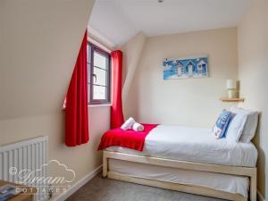 a bedroom with a bed with red curtains and a window at Old Boathouse in Weymouth