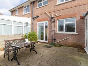 un patio avec un banc en bois devant un bâtiment en briques dans l'établissement The Lookout -The House With A View, à Weymouth