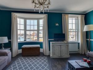 a living room with blue walls and windows at Sailor's Watch in Weymouth