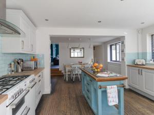 a kitchen with white cabinets and a blue island at Sailor's Watch in Weymouth