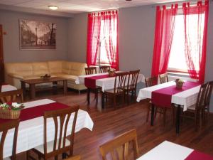 un restaurante con mesas, sofá y cortinas rojas en Salur en Nové Zámky