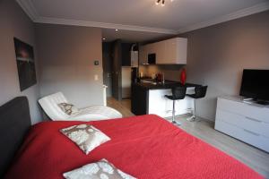 a bedroom with a red bed and a kitchen at Knokke Modern Studio in Knokke-Heist