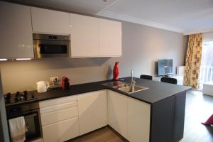 a kitchen with white cabinets and a black counter top at Knokke Modern Studio in Knokke-Heist
