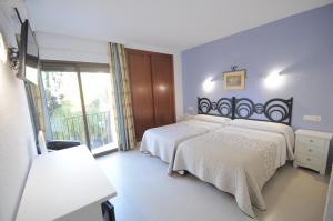 a bedroom with two beds and a large window at Hotel Goya in Almuñécar