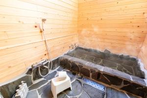 eine Sauna mit einer Badewanne in einer Holzwand in der Unterkunft YUFU-Inn プライベートな露天風呂付き-由布院駅徒歩2分-最大8名宿泊可能 in Yufu
