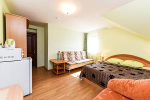 a bedroom with a bed and a couch and a refrigerator at Vila Krantas in Palanga