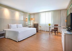a bedroom with a large white bed and a desk at Windsor Plaza Hotel in Ho Chi Minh City