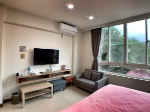 a bedroom with a bed and a tv and a chair at The Sunny Homestay in Puli