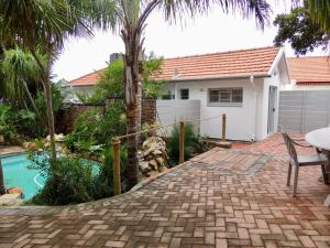 a house with a palm tree and a brick driveway at La Mer Guesthouse in Port Elizabeth