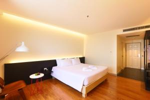 a bedroom with a white bed and a table at Lee Gardens Plaza Hotel - SHA Plus in Hat Yai