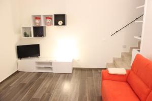 sala de estar con sofá rojo y TV en La Casa del Nespolo, en Ragusa