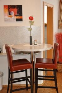 uma mesa com duas cadeiras e um vaso com uma flor em Gasthaus Tauberstube em Rothenburg ob der Tauber
