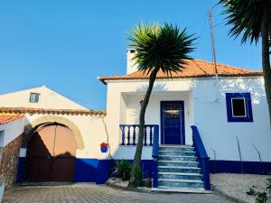 a white house with blue stairs and a palm tree at A Alma Portuguesa in Fátima