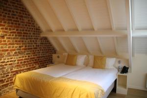 Bett in einem Zimmer mit Ziegelwand in der Unterkunft Hostellerie De Biek in Moorsel