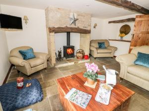 a living room with a fireplace and a table at Five Mile House Barn in Cirencester