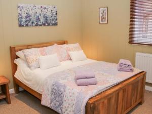 Un dormitorio con una cama con toallas moradas. en Willow River Lodge, en Craven Arms