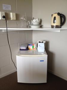 Elle comprend un petit réfrigérateur blanc avec une bouilloire. dans l'établissement Waitomo Golfstays B&B, à Otorohanga