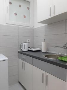 una cocina con armarios blancos y fregadero en Apartment Aurora en Foča