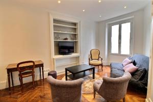 ein Wohnzimmer mit einem Sofa, Stühlen und einem Tisch in der Unterkunft 104525 - Appartement 4 personnes à Paris in Paris