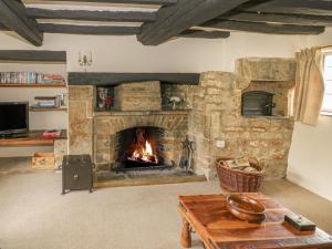 a living room with a stone fireplace and a table at Spring Cottage in Banbury