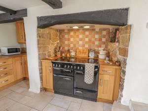 a kitchen with a stove and a stone wall at Spring Cottage in Banbury