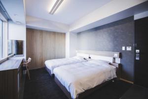 a hotel room with two beds and a window at Hotel Kajiwara in Matsuyama