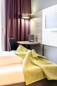 a bedroom with a bed and a desk with a laptop at Hotel Demas City in Munich