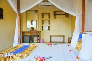 - une chambre dotée d'un lit avec des draps blancs et des fleurs dans l'établissement Filao Beach by Sansi, à Uroa
