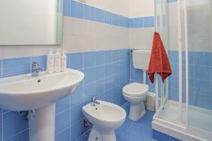 Un baño con azulejos azules, lavabo e inodoro. en Seaview Rooms in the center by Wonderful Italy, en Cefalú