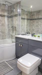 a bathroom with a toilet and a tub and a sink at V2 Apartments Park Row in Leeds