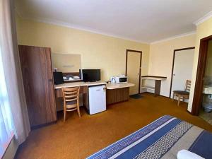 ein Hotelzimmer mit einem Bett und einem Schreibtisch mit einem Kühlschrank in der Unterkunft Donnybrook Motel in Donnybrook