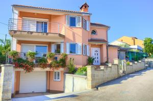 ein rosafarbenes Haus mit einem Balkon und einer Garage in der Unterkunft Apartment Vjeko in Vantačići