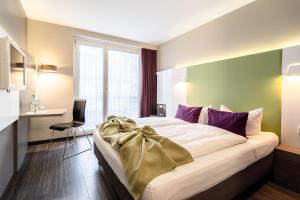 a bedroom with a large bed and a large window at Hotel Demas City in Munich