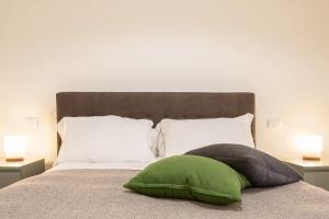 ein grünes Kissen auf einem Bett mit zwei Lampen in der Unterkunft Appartamento al Consiglio Reginale by Wonderful Italy in Syrakus