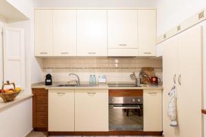 una cocina con armarios blancos y fregadero en Appartamento al Consiglio Reginale by Wonderful Italy, en Siracusa
