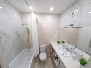 a white bathroom with a toilet and a sink and a tub at СУЧАСНА НОВА КВАРТИРА in Lutsk +35 photos