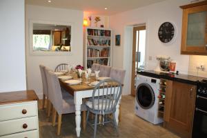 a kitchen with a dining room table with chairs and a washing machine at Linton Luxury Holiday Home in Mevagissey