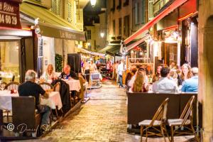 um grupo de pessoas sentadas a mesas numa rua à noite em Appartement Cannes em Cannes