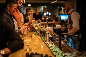 a group of people sitting at a bar looking at their phones at Hotel Leifur Eiriksson in Reykjavík