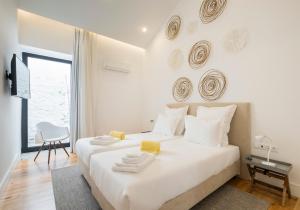a white bedroom with a white bed and a window at Aqua - Pópulo Eco Village in Ponta Delgada