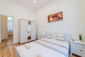 Habitación blanca con cama y espejo en Real Apartments Anker, en Budapest
